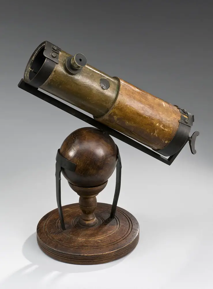 Replica of Newton's first reflecting telescope made in 1668. Full view, graduated grey background.